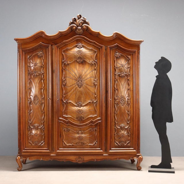 Late Baroque walnut wardrobe. Three-door paneled front, richly carved with scrolls, leaves, and curls; center door with...