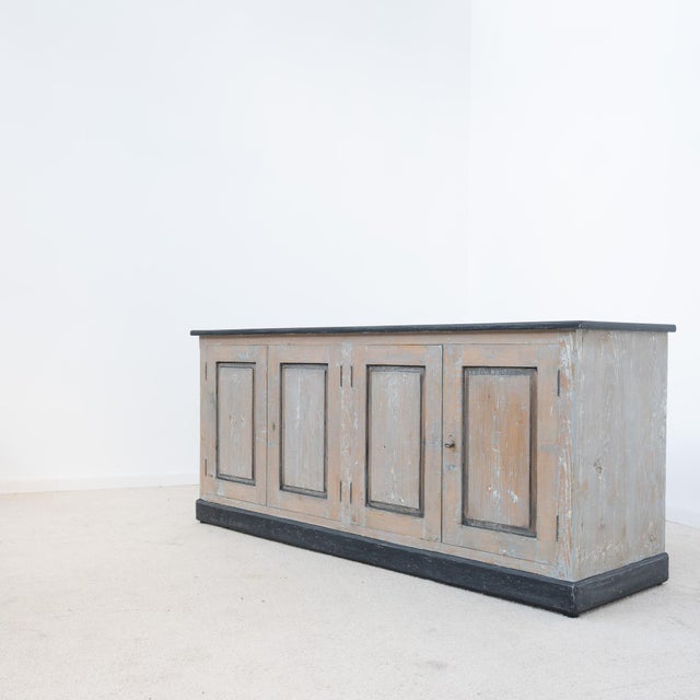 A low sideboard dating from the early 20th century, preserved in a beautiful antique patina of beige, gray, and black...