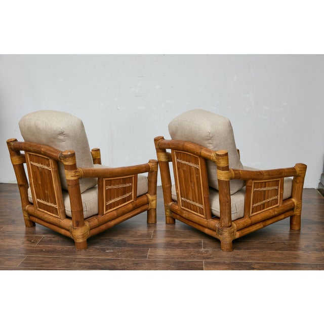 A set of two bamboo lounge chairs with their ottoman from the Midcentury period, with rattan accents and custom linen...