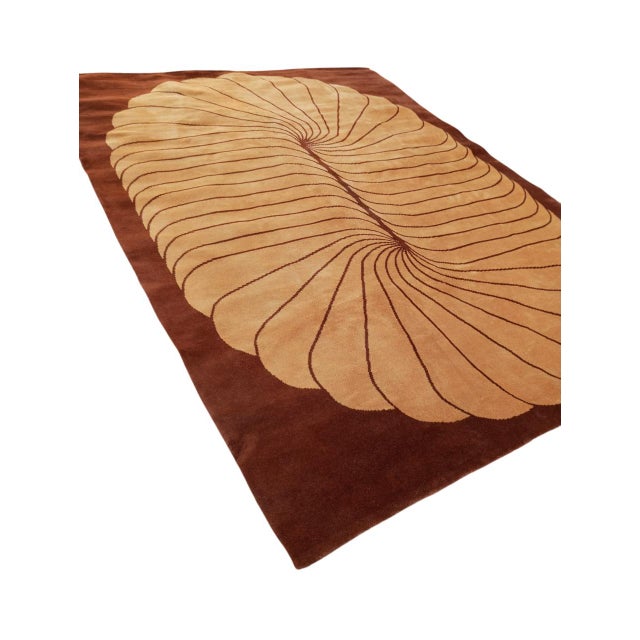 Wool rug with a dark brown background, featuring a beige oval figure at the center, composed of a series of curved,...