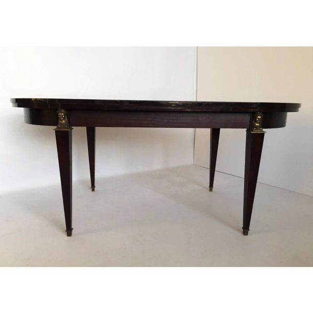 Exceptional modern dining room table in rosewood. The table is oval in shape, with a headband, on square tapering legs...