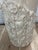 Sculptural vintage pedestal featuring a cylindrical silhouette clad in tessellated stone in warm cream and sand tones. A...