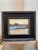 This oil on panel artwork captures a serene island landscape at sunset, with soft hues of pink and orange reflecting on...
