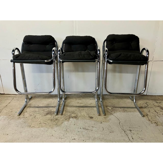 These barstools feature tubular chrome frames with black canvas seat cushions supported by canvas slings. There are no...