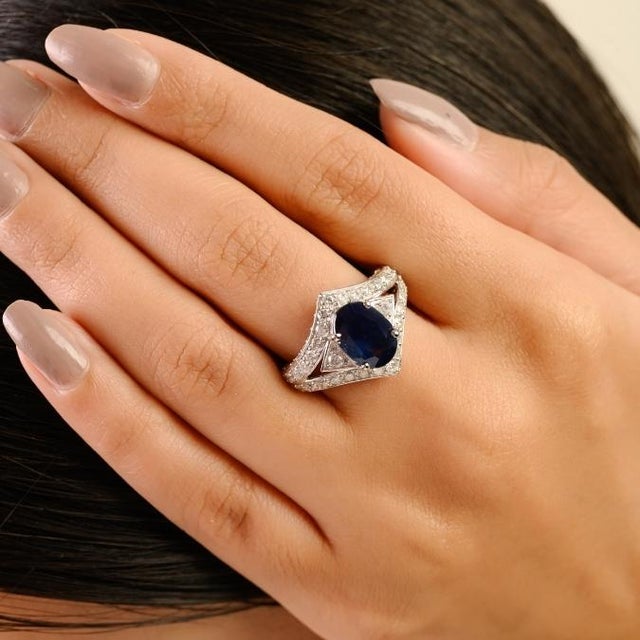 This Art Deco-style cocktail ring features a 2.6-carat oval-cut deep blue sapphire as the center stone, set in a secure...
