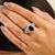 This Art Deco-style cocktail ring features a 2.6-carat oval-cut deep blue sapphire as the center stone, set in a secure...