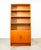 Functional compact bookshelf in teak. Bottom section offers cabinet doors with solid teak handles. The above bookshelf...