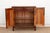 Two recessed door panels finished in a saturated red sit within a darker brown-black lacquered frame on this cabinet,...
