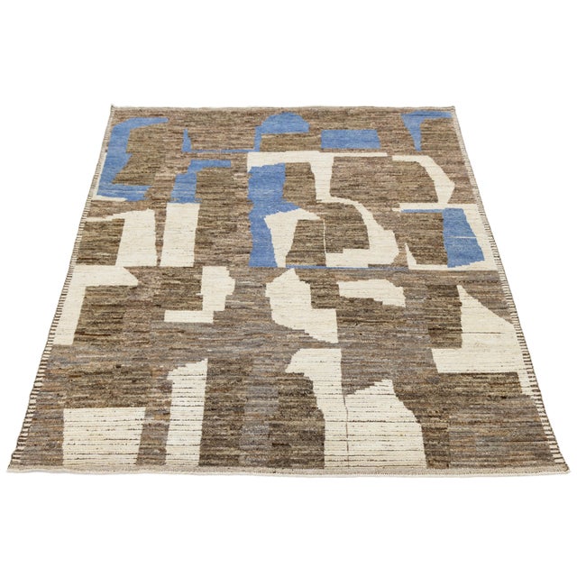 Handwoven in wool, this modern Moroccan-style rug features an abstract composition of earthy browns, off-white, and...