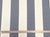 This designer fabric features a classic stripe pattern with a woven texture. The fabric has alternating stripes of navy...