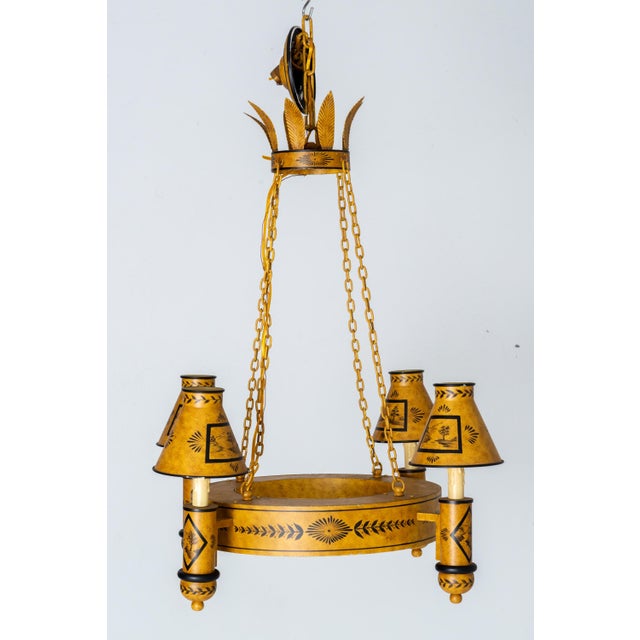 A striking vintage gold and black tole chandelier with four lights, featuring flared metal shades and dates back to the...
