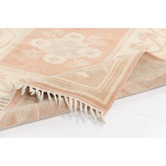 This is a vintage Turkish Oushak rug from the Mid 20th Century. The piece was hand-knotted.