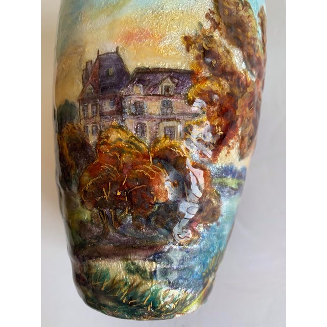 The vase depicts a French countryside landscape with a classic chateau surrounded by trees under a beautiful blue sky. The...