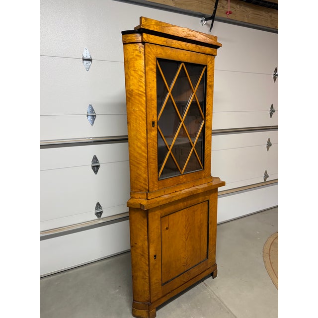 Flamed birch Biedermeier corner cabinet dated 1820-1850. Acquired from the French Consulate in Chicago, circa 1930s–1950s,...