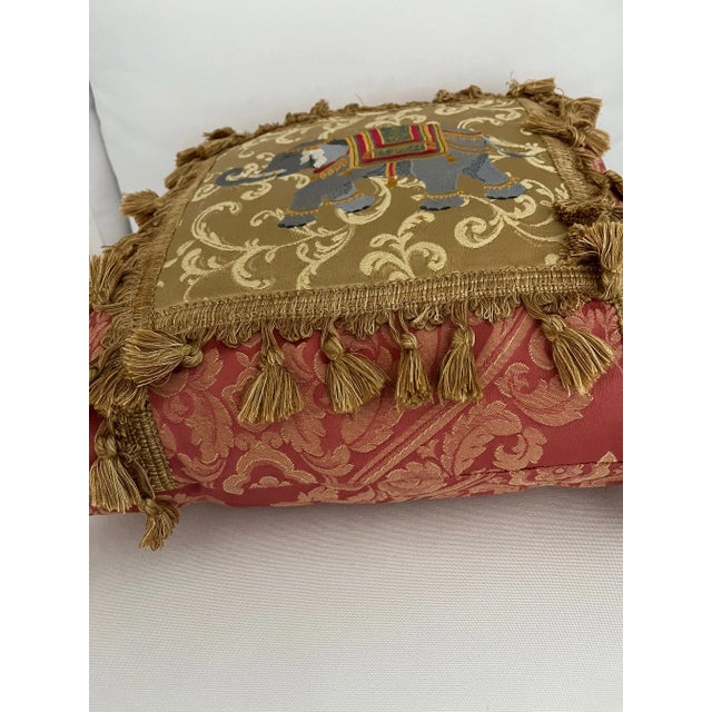 Deep rose and gold throw pillow with exuberant tasseled braid trim and proud bedecked elephant makes an elegant statement....