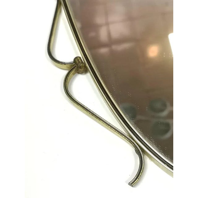 Graceful metal framed wall mirror with minimalist decorations from the 1950s.