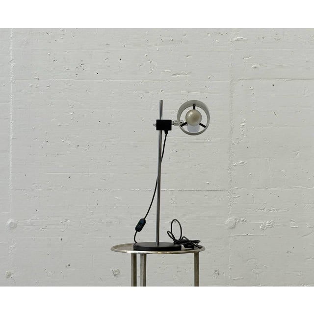 Industrial-style table lamp from the 1970s. The lamp is mounted on a round metal base and consists of a chrome-plated or...