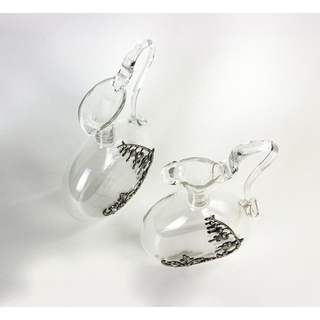 Vintage pair of Glass Jugs. Silver decorations. 22 x 12,5 cm; 21 x 12 cm. Italy 1970s. Very Good condition escept for some...