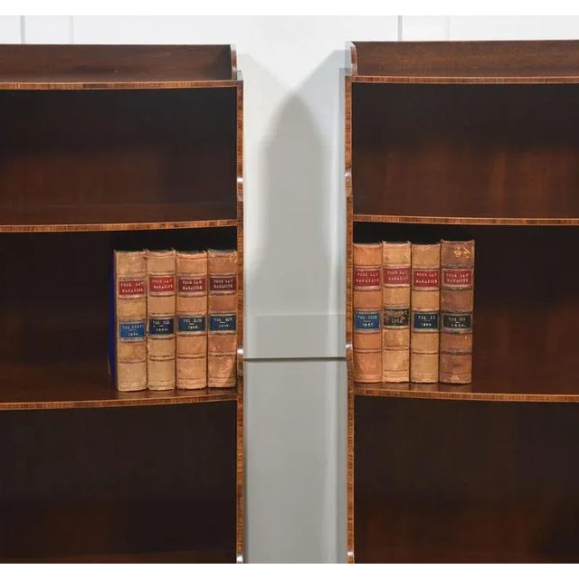 A handsome pair of mahogany waterfall bookcases. Each piece is designed with three graduated open shelves, their sides...