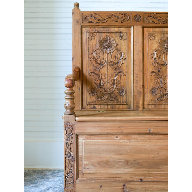 This lovely piece is a vintage English pine settle or storage bench, featuring carved daisy and leaf motifs. Crafted from...