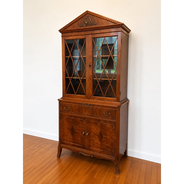 Elegant vintage china cabinet featuring beautiful wood grain, diamond-pane glass doors, and refined Federal-style...
