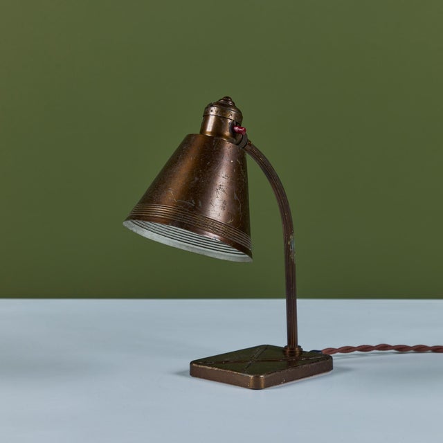 Brass desk lamp for Chase, c.1930s, USA. The Art Deco lamp features a curved stem and cone shade. The lamp has a...