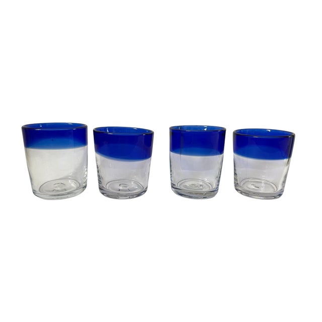 This is a set of eight handmade Mexican glass tumblers with a rustic style. The glasses have a round shape and are made of...