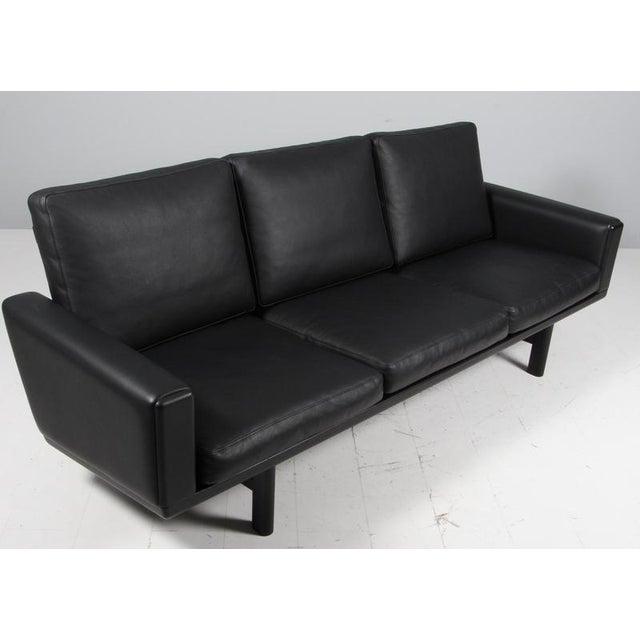 Hans J. Wegner three-seat sofa original upholstered with black leather. Frame in solid black oak. Model 236/3, produced by...