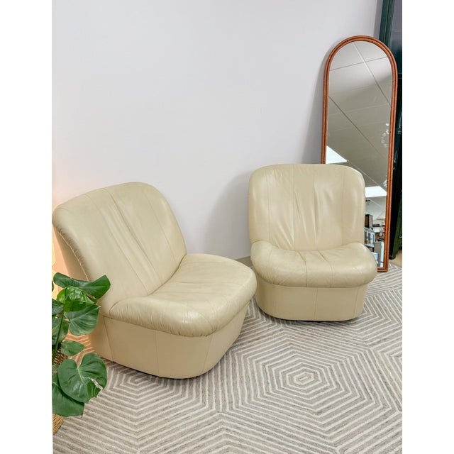 This attractive pair of vintage cream leather MCM postmodern swivel glider chairs are a comfortable and stylish retro...