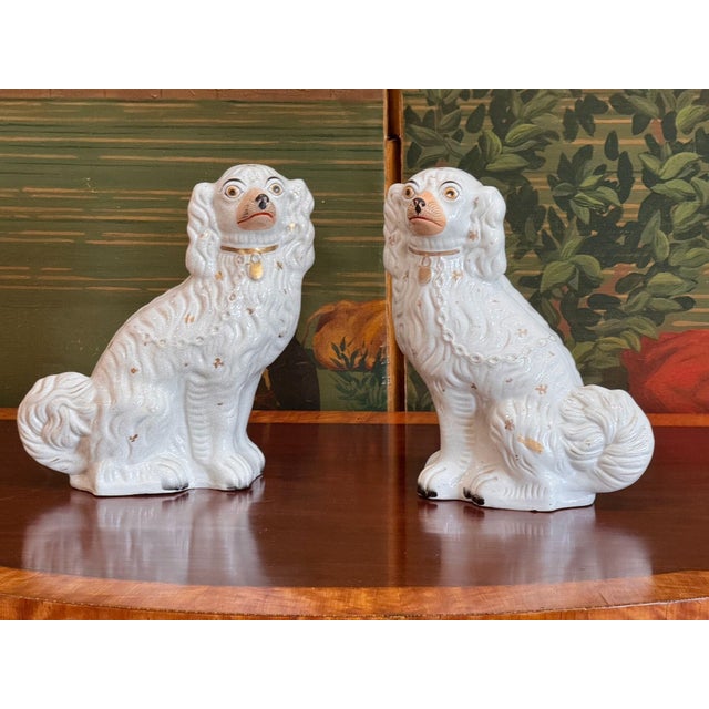 A pair of Victorian English Staffordshire pottery spaniels, sitting upright and facing each other, glazed in white with...