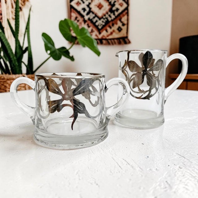 Elevate your dining experience with this exquisite Vintage Art Nouveau Silver Overlay Creamer and Sugar Bowl Set,...