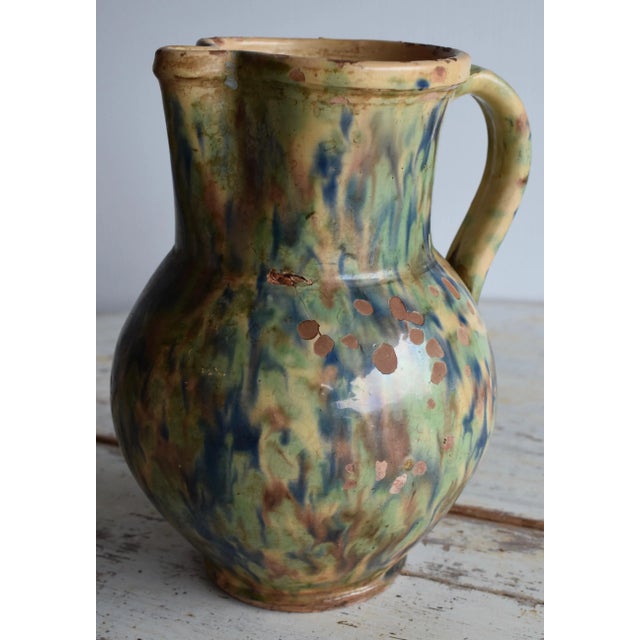 19th Century French Jaspe multicolored glazed pitcher in terracotta with greens, browns, blues and yellow. The pitcher has...