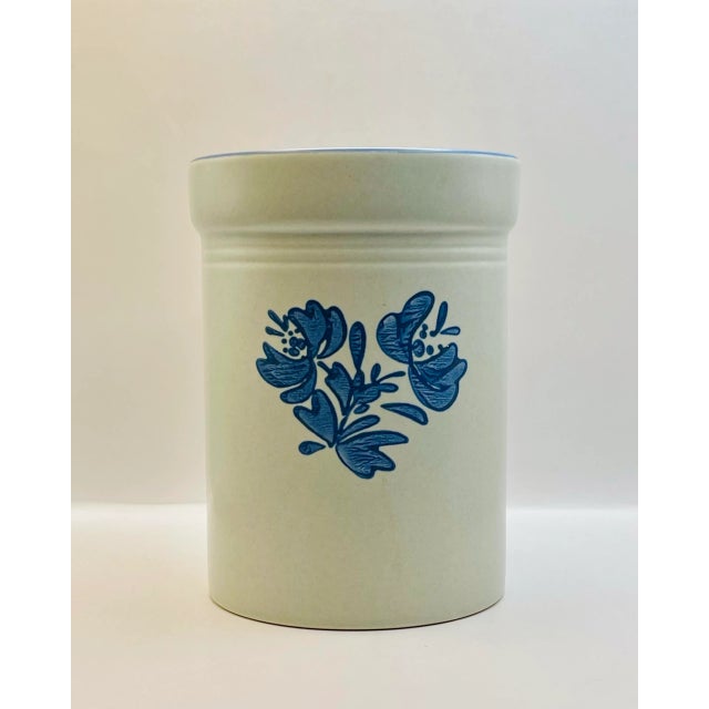 A vintage beige utensil crock decorated with a spray of cobalt blue flowers.