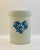 A vintage beige utensil crock decorated with a spray of cobalt blue flowers.