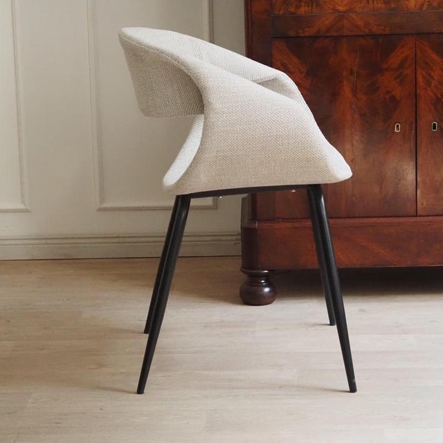 The chair is a newly produced piece of seating furniture with a fully upholstered shell body and an open cutout in the...