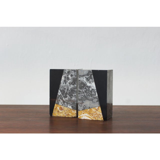 A pair of Art Deco-style bookends made of natural marble with varied patterns and colors. The composition consists of...