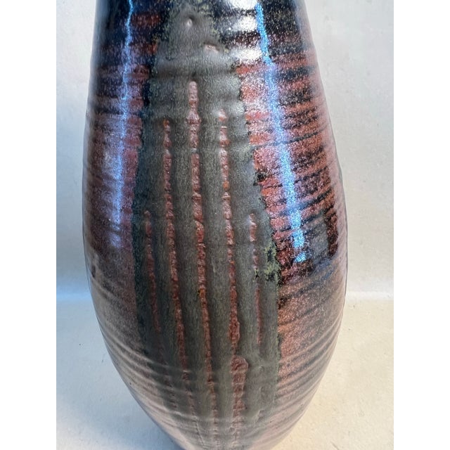 Signed on base “plunkett.” Hand-thrown studio stoneware vase with a tall ovoid form and flared collar rim. Finished in a...