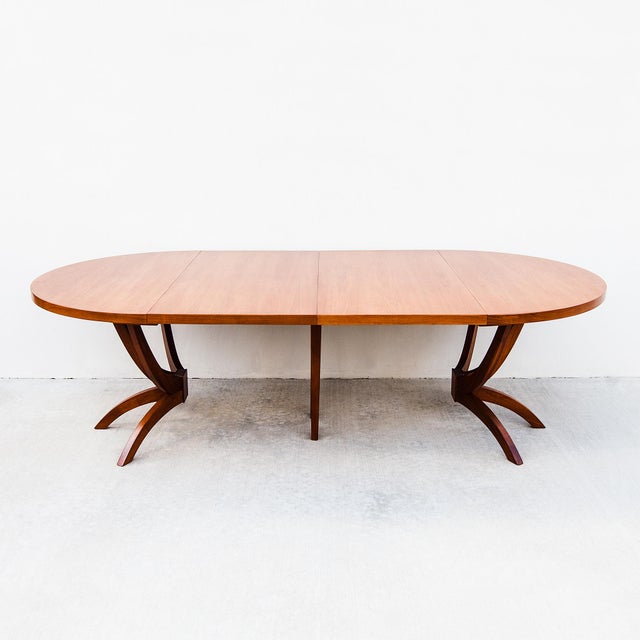 A beautifully refinished expandable walnut dining table with three large leaf extensions, made in the United States c....