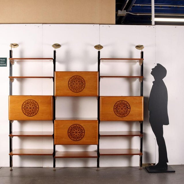 Vintage bookcase with wall anchoring system composed of stained wooden uprights with enamelled metal fixing elements,...