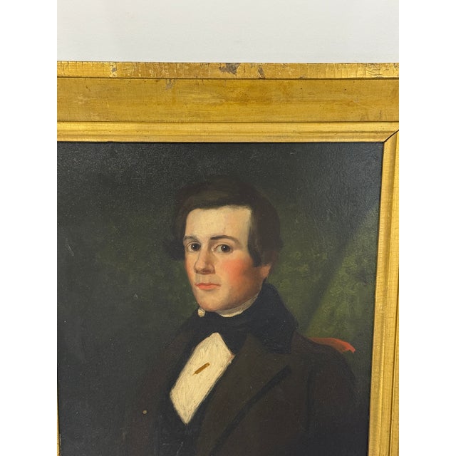 A mid-19th-century American Folk Art oil on board portrait of an unidentified young gentleman, in the New England School...