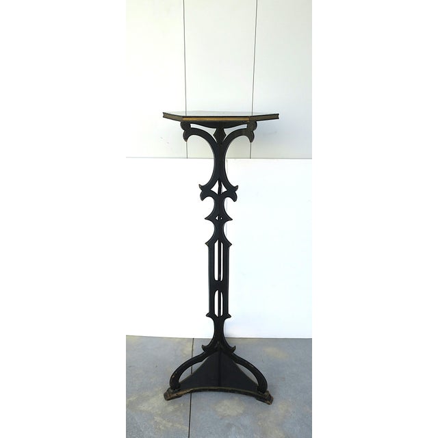 A column wood pedestal plant stand finished in a black lacquer with gold accents, Victorian design period, circa late-19th...