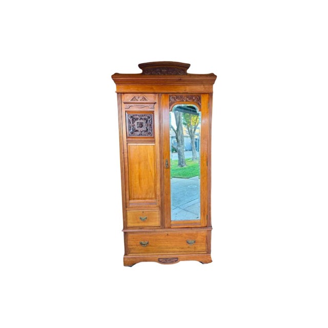 Antique c.1900's Edwardian Wardrobe Cabinet. This warm toned solid wood cabinet features ornate carvings, a full-length...