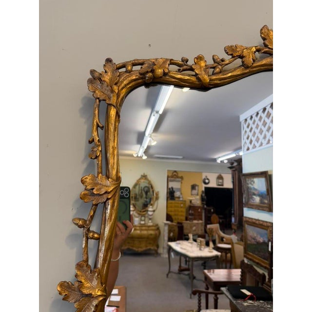 Striking 19th-century French gilded mirror, circa 1890, featuring an ornately hand-carved wood frame with an elegant oak...