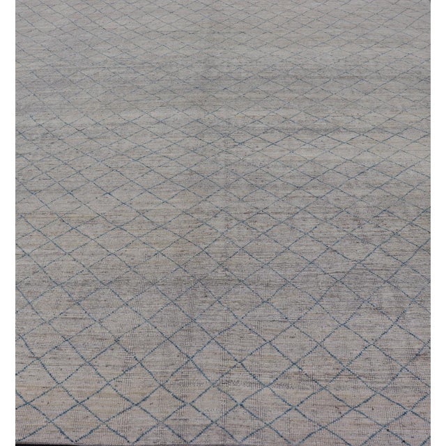 Measures: 10'2 x 13'6. This modern casual tribal rug has been hand-knotted in wool. The rug features a modern all-over...