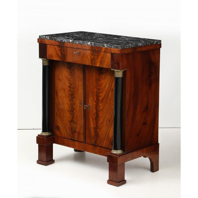 Neoclassical two door cabinet. Flame Mahogany with original Brass mounts and marble top, (of a latter replacement). Early...