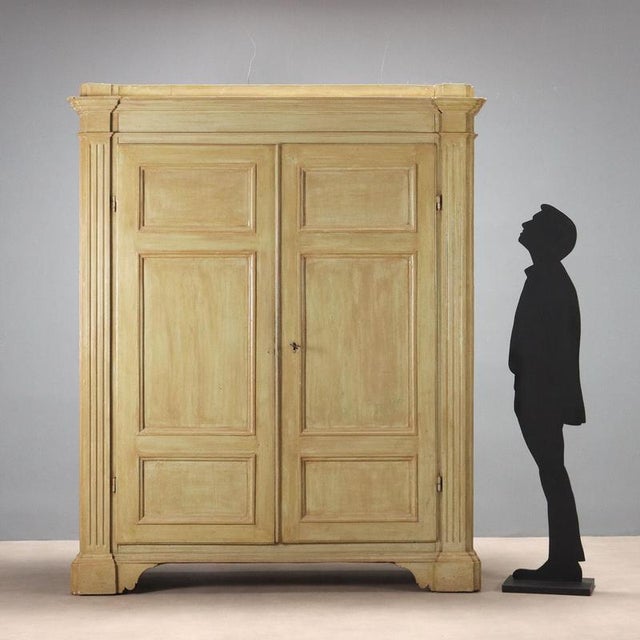 Baroque wardrobe in green lacquered poplar. Front with a pair of tripartite paneled doors and carved uprights, bracket...