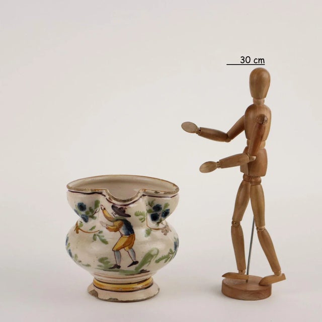 Ligurian-made majolica jug with globular body, expanded edge and spout. Spool handle. The jug is decorated in polychrome...