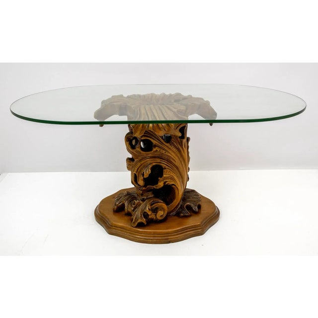 Mid-century modern coffee table with carved wooden base, large curls and leaves, thick thick oval shape crystal. 1950s