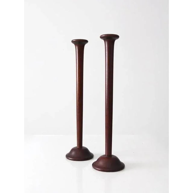 This pair of vintage wooden candlesticks features tall, dark wood taper candle holders with round pedestal bases and...