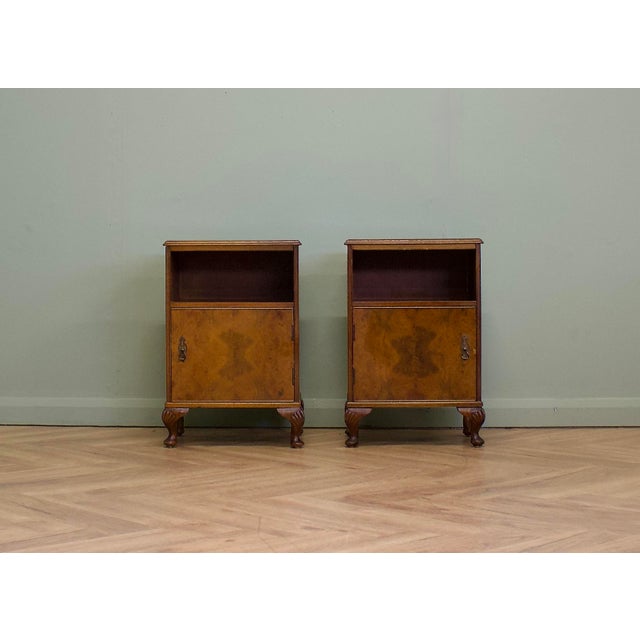 A matching pair of 1930s bedside cabinets featuring burr walnut doors, open upper shelves and cupboards below. Finished...